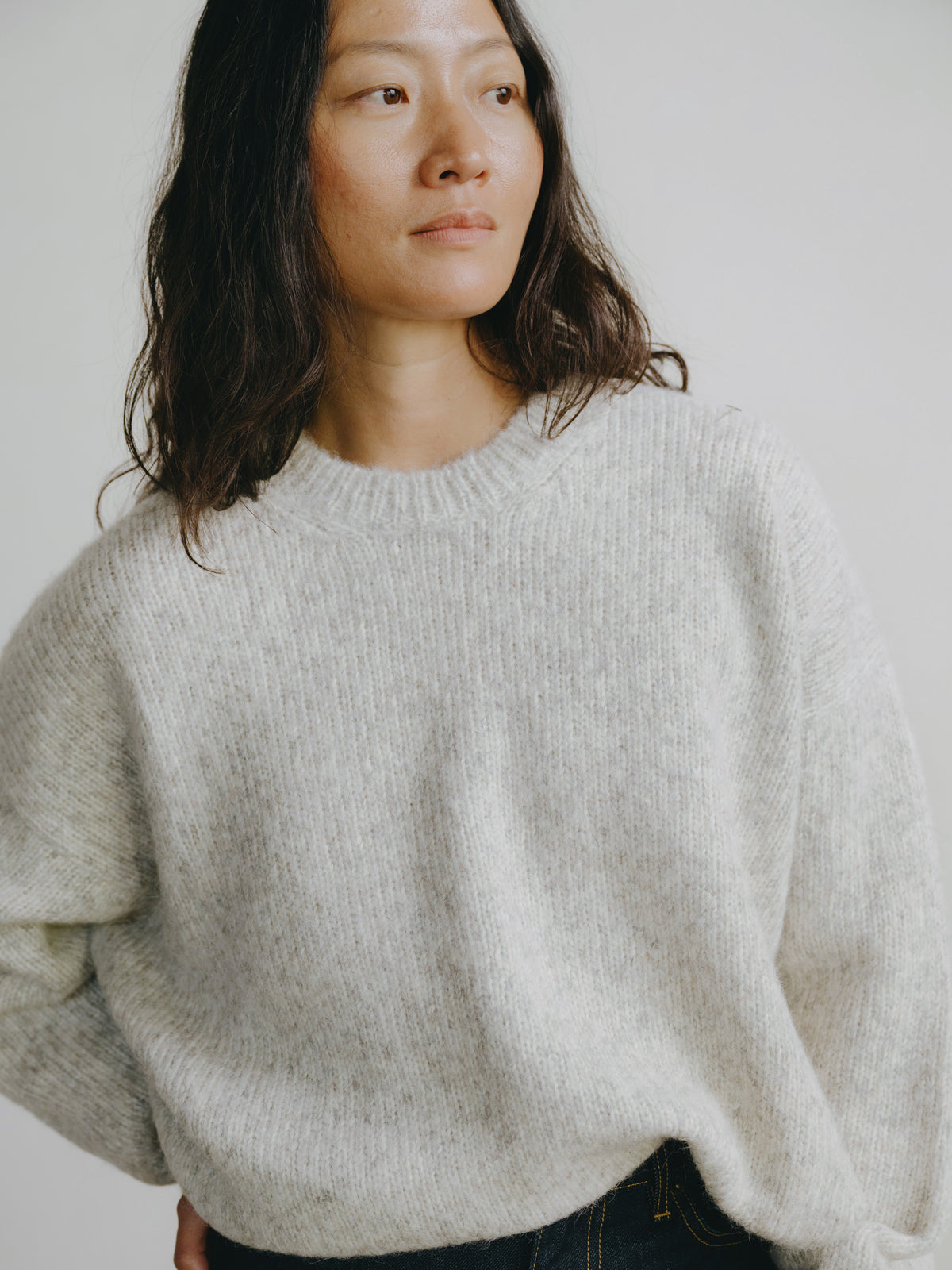 Woman wearing a light gray sweater against a plain background