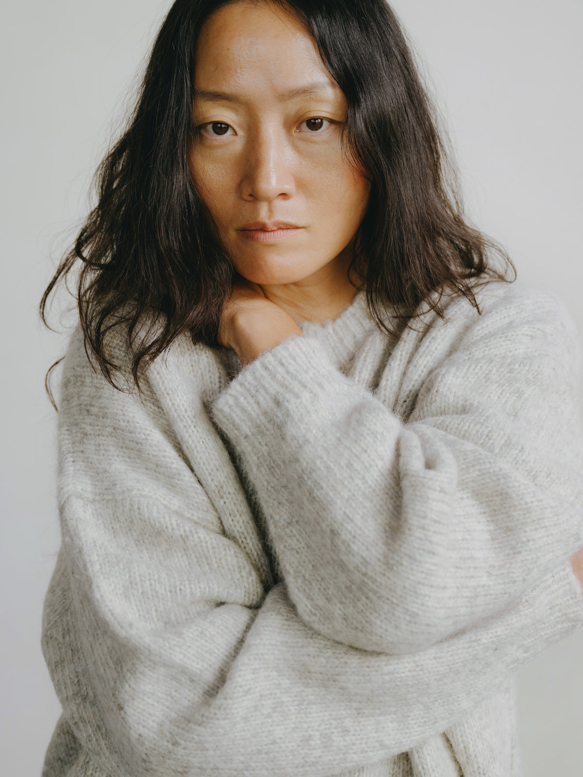 Woman wearing a light gray sweater against a plain background