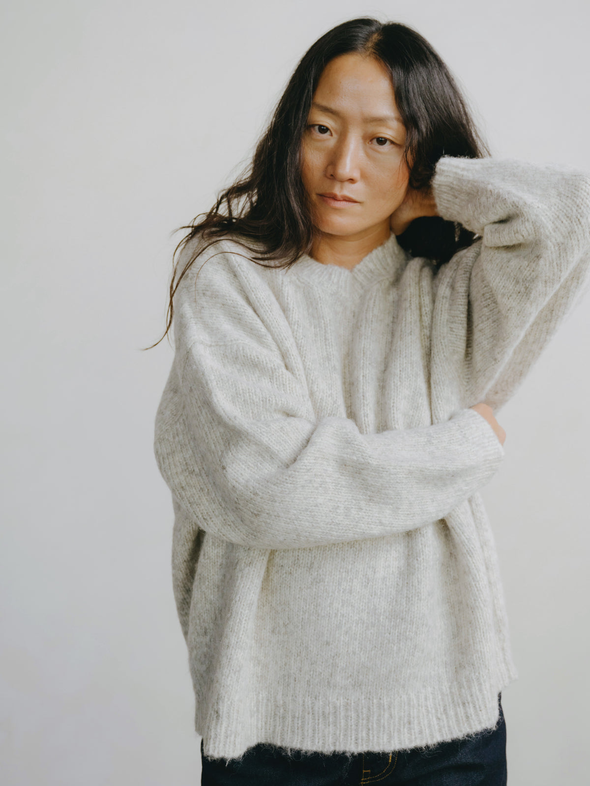 Woman wearing a light gray sweater against a plain background