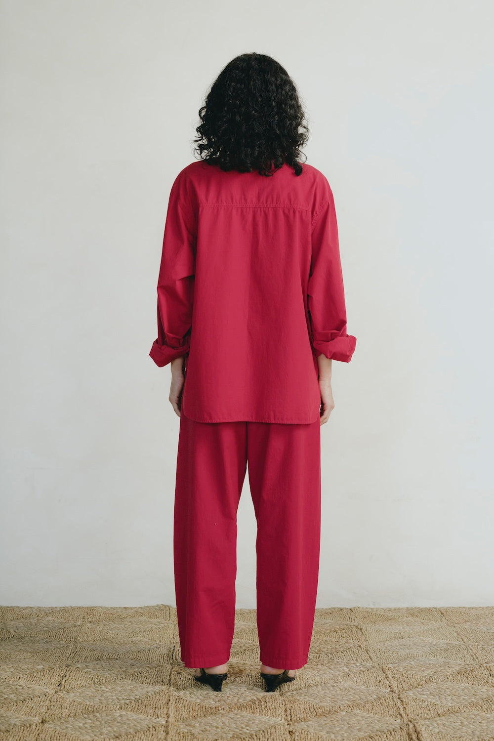 Person wearing a red outfit standing against a plain background