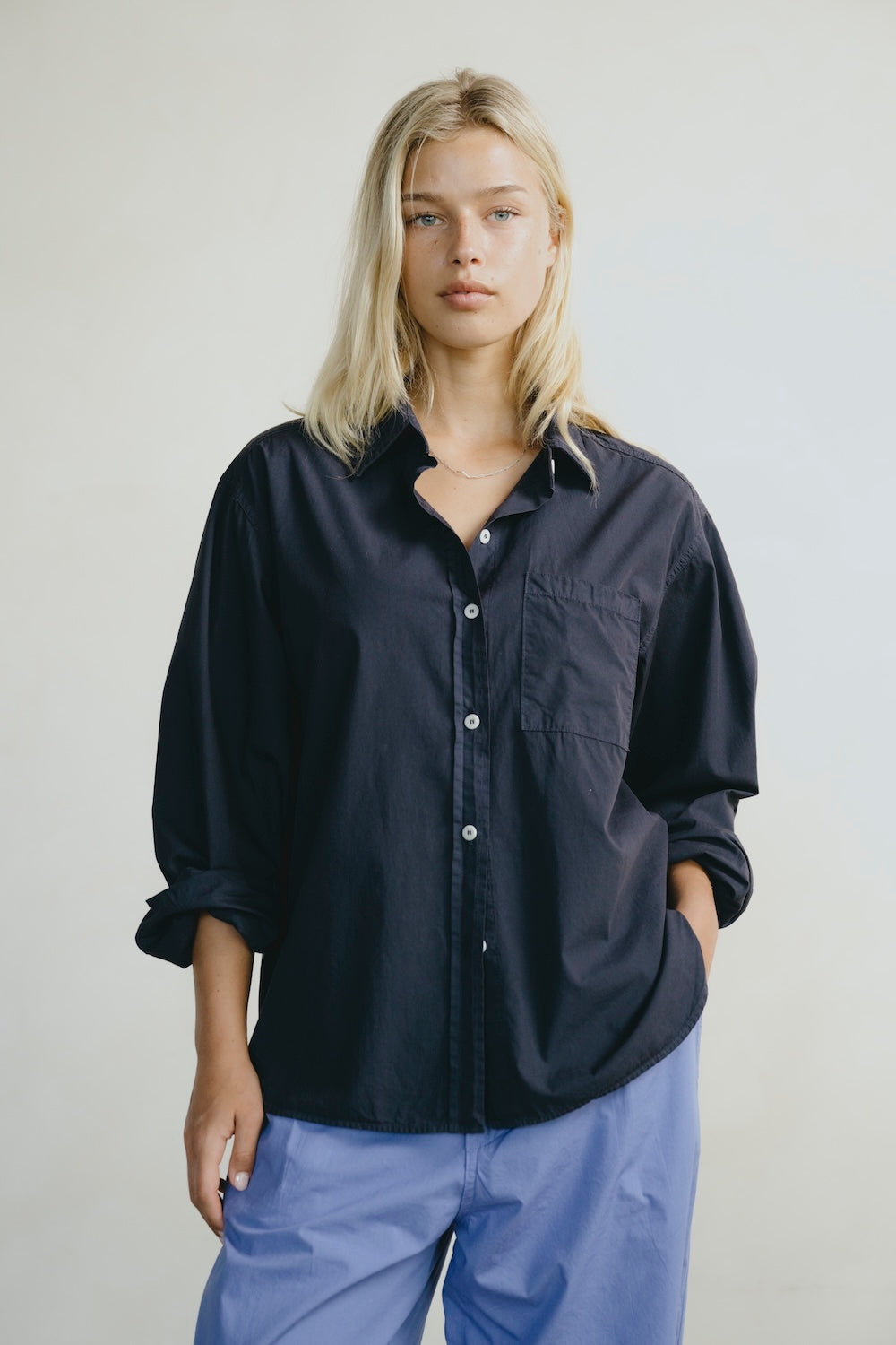 Person wearing a black shirt and blue pants against a plain background