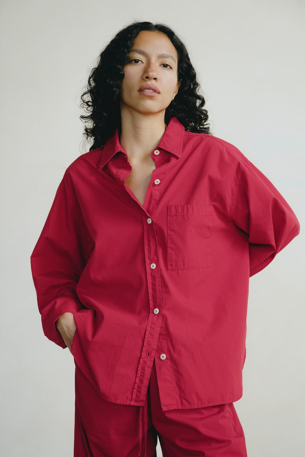 Person wearing a red shirt and pants against a plain background