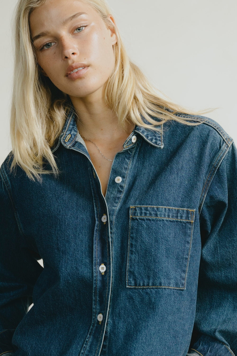 Woman wearing a denim shirt against a plain background